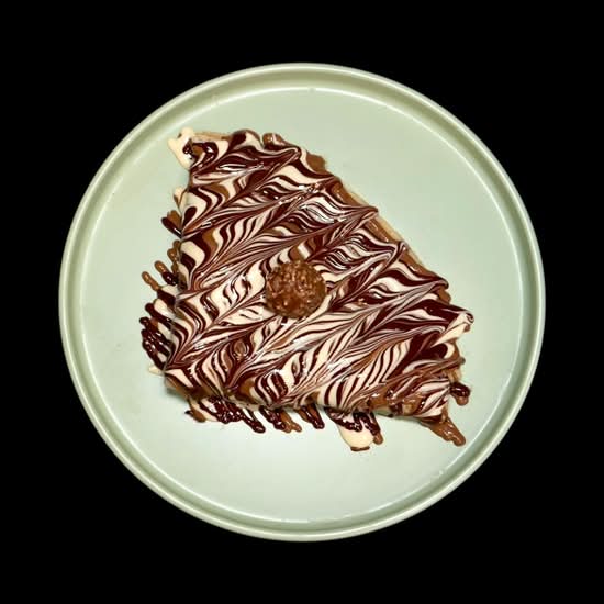 Cocomelt FOMO crepe with layered chocolate drizzles on a green plate