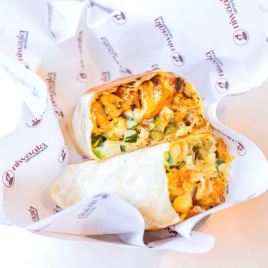 Niwaala's halved tandoori chicken shawarma wrap with cucumber and sauce in branded paper