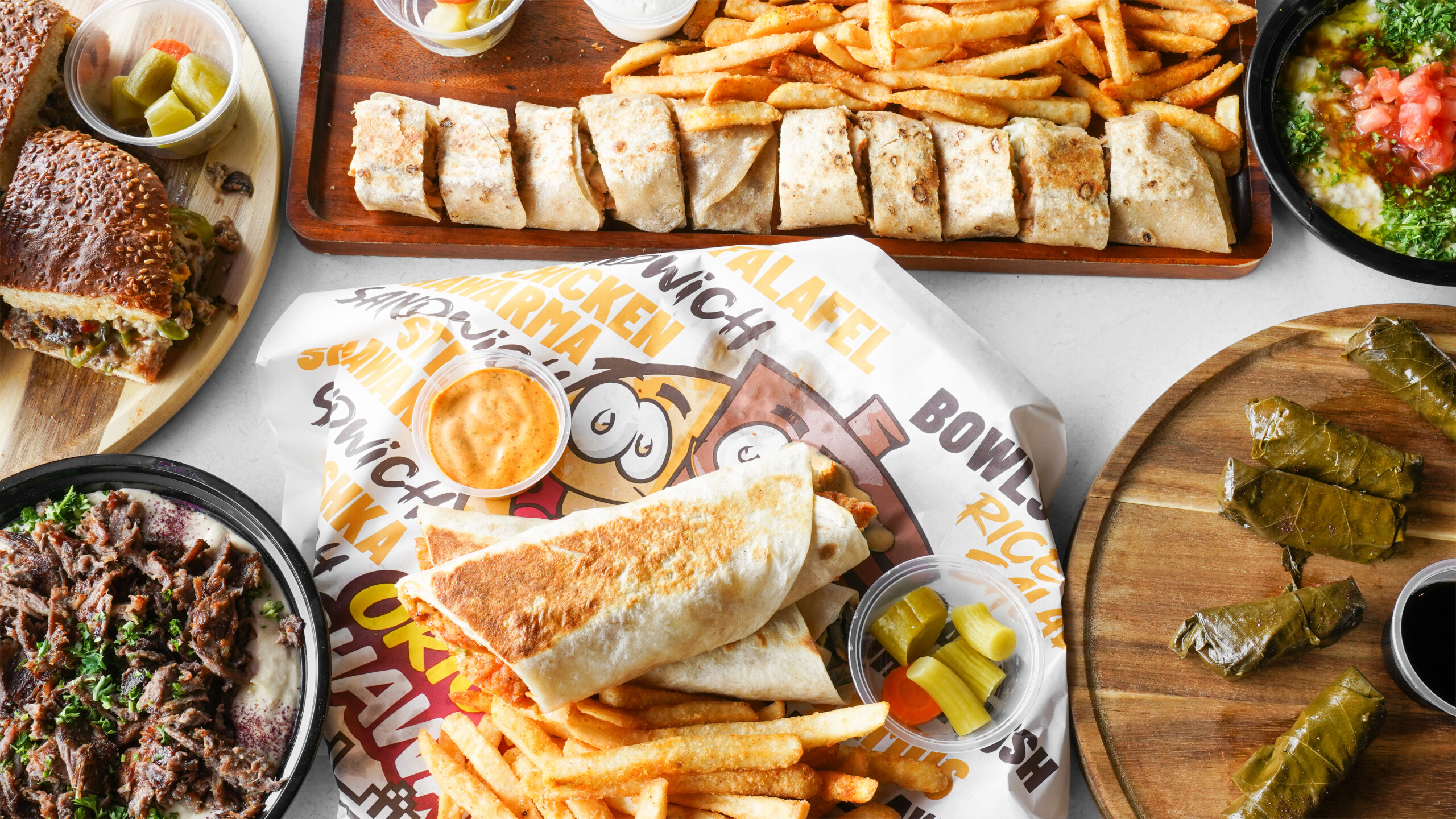 Original Shawarma restaurant spread with sandwiches, sliced wraps, fries, dips and grape leaves